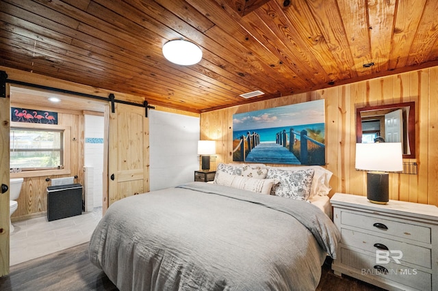 bedroom with connected bathroom, wood ceiling, a barn door, and wood walls