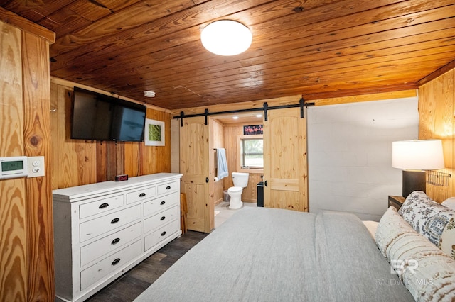 bedroom featuring wooden ceiling, wooden walls, ensuite bath, dark hardwood / wood-style floors, and a barn door