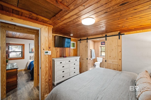 bedroom featuring connected bathroom, dark wood-type flooring, a barn door, wooden walls, and wood ceiling