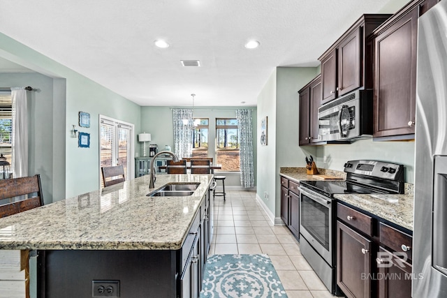 kitchen featuring a kitchen island with sink, light stone counters, stainless steel appliances, and sink