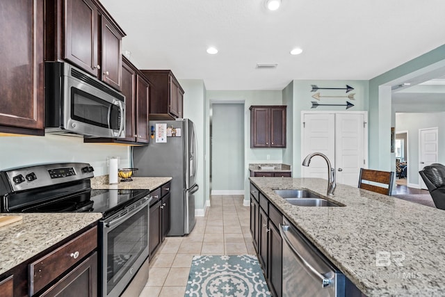 kitchen featuring light stone counters, stainless steel appliances, sink, and light tile patterned floors