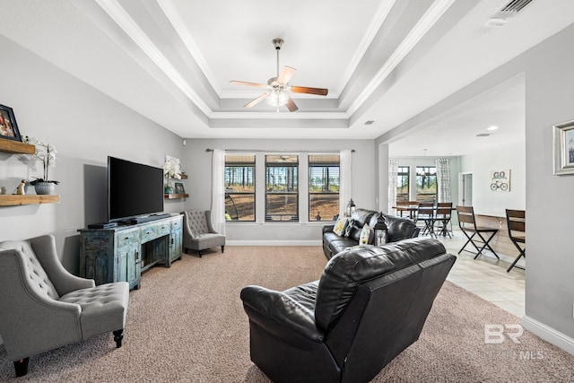 carpeted living room with a tray ceiling, ornamental molding, and ceiling fan