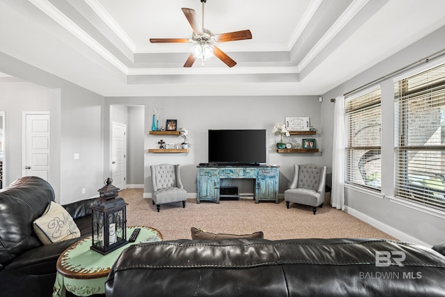 carpeted living room featuring a raised ceiling, ceiling fan, and ornamental molding