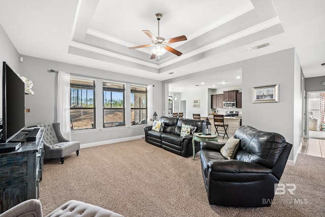 living room with crown molding, ceiling fan, light carpet, and a tray ceiling