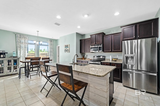 kitchen featuring pendant lighting, a chandelier, stainless steel appliances, light stone counters, and sink