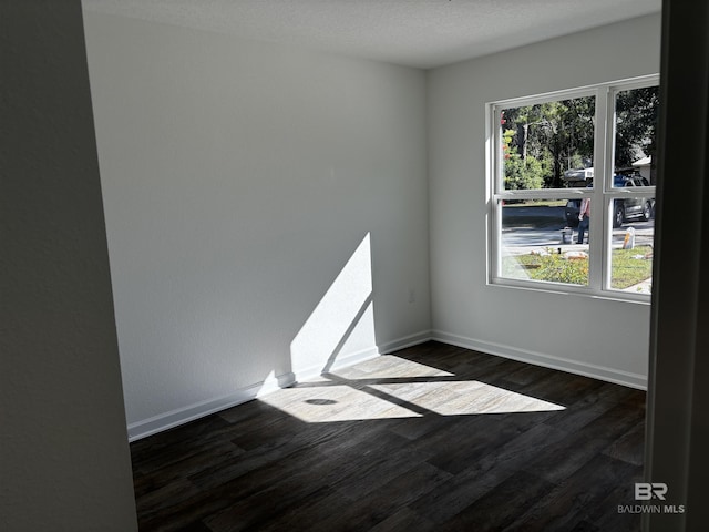 unfurnished room featuring dark wood-type flooring, a healthy amount of sunlight, and a textured ceiling