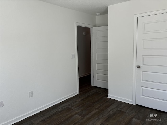 unfurnished bedroom with dark wood-type flooring and a textured ceiling