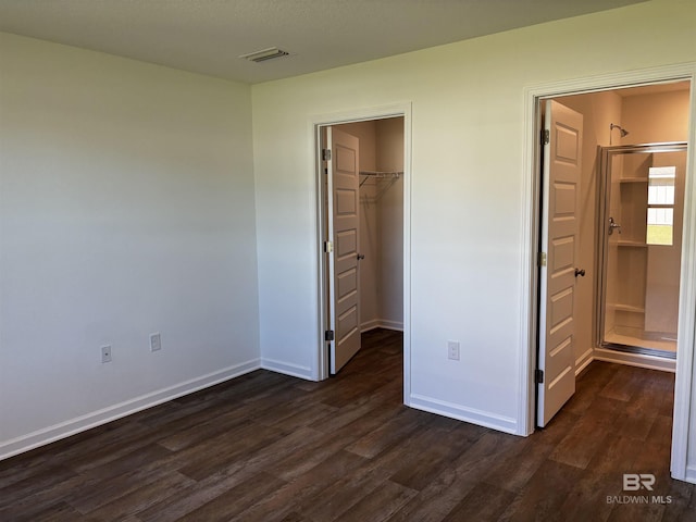 unfurnished bedroom with a walk in closet, dark hardwood / wood-style floors, and a closet