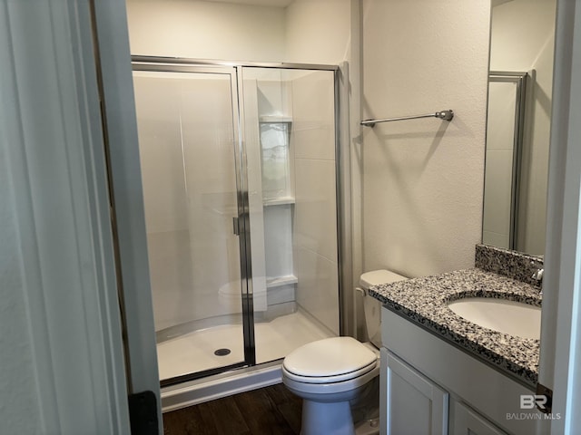 bathroom featuring vanity, hardwood / wood-style flooring, a shower with door, and toilet