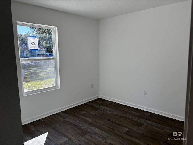 spare room featuring dark wood-type flooring and a textured ceiling