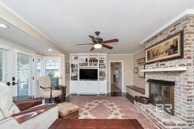 living room featuring a textured ceiling, a brick fireplace, ceiling fan, and ornamental molding