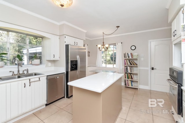 kitchen with stainless steel appliances, sink, pendant lighting, white cabinetry, and a kitchen island