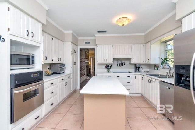 kitchen featuring white cabinetry, a center island, sink, stainless steel appliances, and ornamental molding