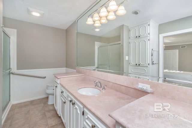 bathroom featuring tile patterned floors, vanity, toilet, and a shower with door