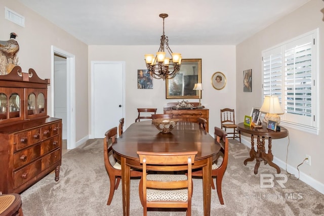 carpeted dining area with a chandelier