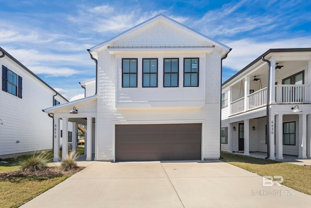 view of front of property with a garage, driveway, a balcony, and a ceiling fan