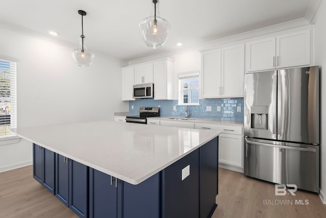 kitchen featuring appliances with stainless steel finishes, a sink, a wealth of natural light, and blue cabinets