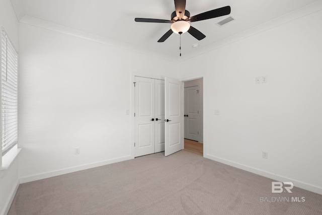 unfurnished bedroom with light colored carpet, visible vents, crown molding, and baseboards