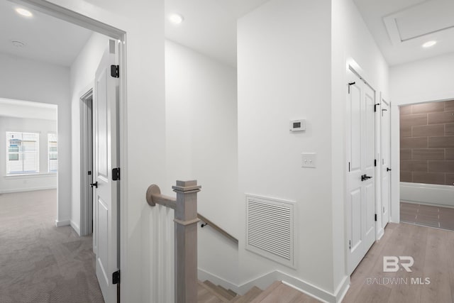 corridor with visible vents, baseboards, an upstairs landing, light wood-type flooring, and recessed lighting