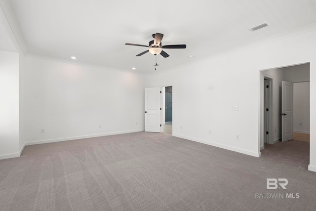 carpeted empty room with a ceiling fan, visible vents, ornamental molding, and baseboards