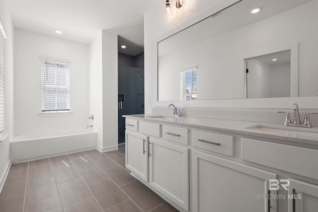 bathroom featuring double vanity, a sink, a bath, and recessed lighting