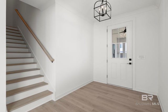 foyer entrance with a chandelier, stairway, wood finished floors, and baseboards