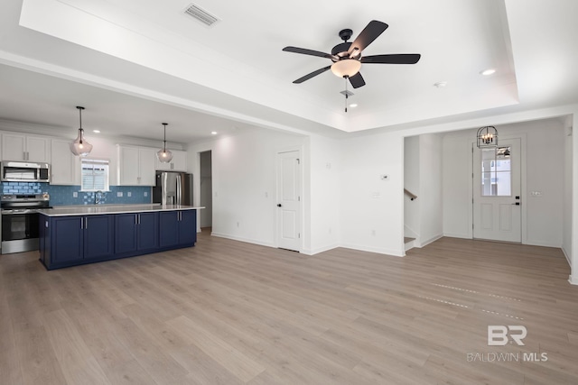 interior space featuring visible vents, a tray ceiling, stainless steel appliances, and light countertops