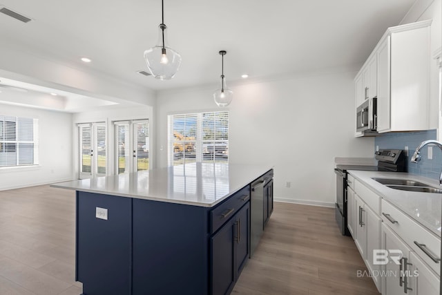 kitchen with stainless steel appliances, a sink, backsplash, a center island, and light wood finished floors