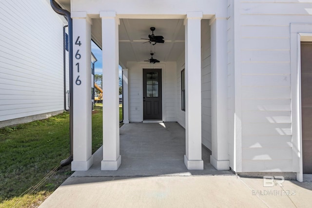 doorway to property with covered porch, a lawn, and a ceiling fan