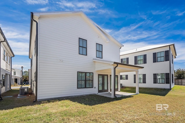 rear view of property featuring cooling unit, french doors, a patio area, and a yard