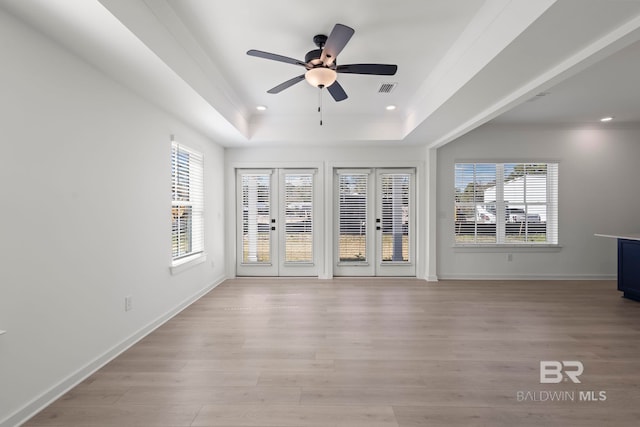 interior space featuring a tray ceiling, light wood-style flooring, baseboards, and recessed lighting