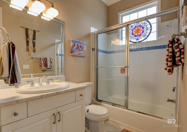 full bathroom with combined bath / shower with glass door, tile patterned floors, vanity, and toilet