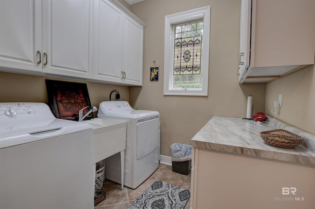 laundry area featuring cabinets, light tile patterned flooring, and washing machine and dryer