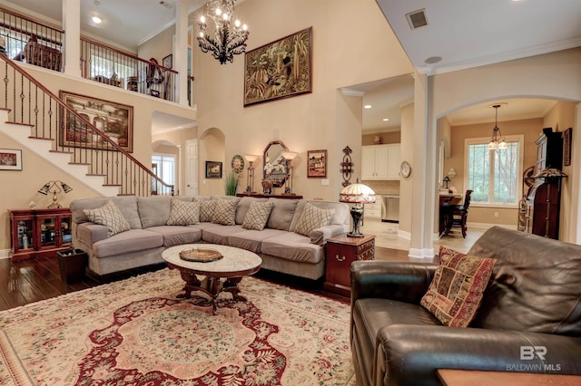 living room featuring hardwood / wood-style flooring, crown molding, a towering ceiling, and an inviting chandelier