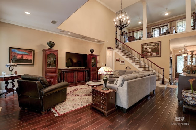 living room featuring crown molding, a towering ceiling, dark wood-type flooring, and an inviting chandelier