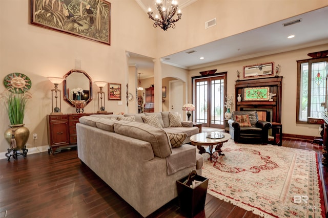 living room with dark hardwood / wood-style flooring, ornamental molding, a wealth of natural light, and an inviting chandelier