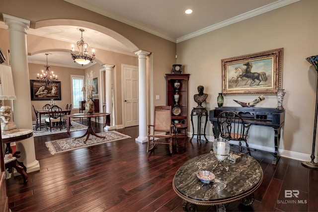 living area with dark hardwood / wood-style floors, decorative columns, ornamental molding, and an inviting chandelier