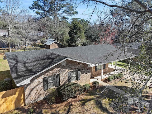 212 Lee St, Fairhope, AL 36532 - view of home's exterior featuring roof with shingles, fence, brick siding, a shed, and an outbuilding