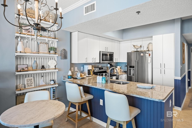 kitchen with a peninsula, light tile patterned floors, a sink, visible vents, and appliances with stainless steel finishes