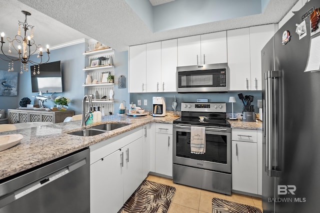 kitchen with an inviting chandelier, a sink, white cabinets, appliances with stainless steel finishes, and light tile patterned flooring