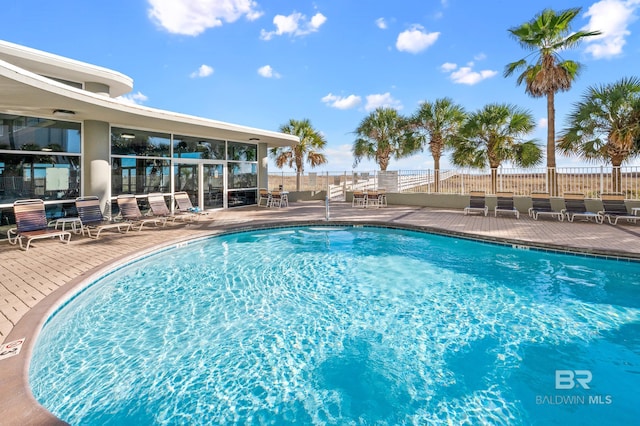 pool featuring a sunroom, a patio, and fence