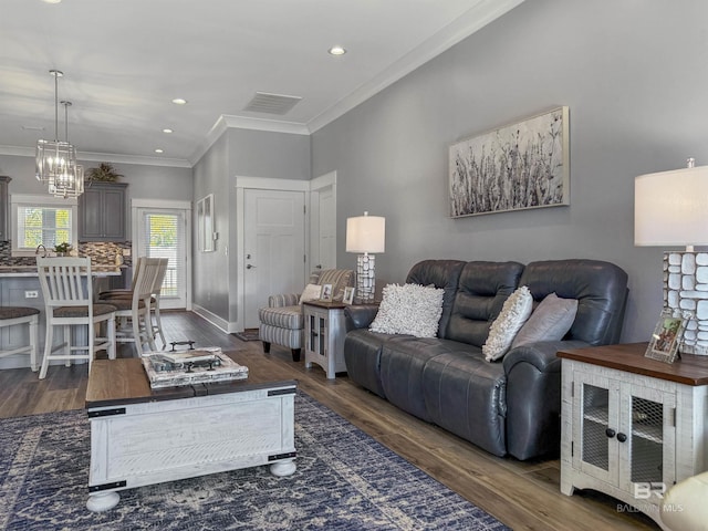 living room with dark hardwood / wood-style floors, crown molding, and a notable chandelier