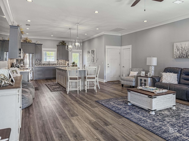 living room featuring ceiling fan with notable chandelier, dark hardwood / wood-style floors, and ornamental molding