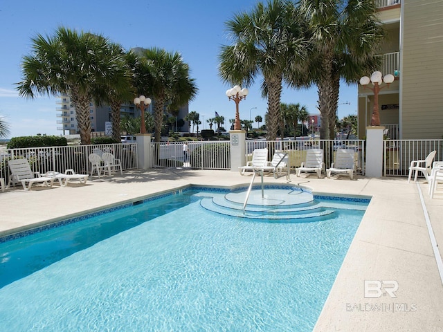 pool with a patio area and fence