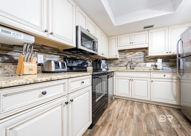 24132 Perdido Beach Blvd Unit 1024, Orange Beach, AL 36561 - kitchen with visible vents, white cabinetry, appliances with stainless steel finishes, light wood finished floors, and decorative backsplash