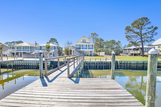 view of dock with a water view, a residential view, and a yard