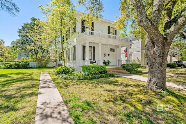 view of front of property featuring a balcony, a front lawn, and a porch