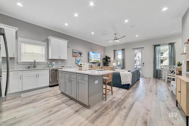 kitchen with a sink, stainless steel dishwasher, plenty of natural light, and a kitchen island