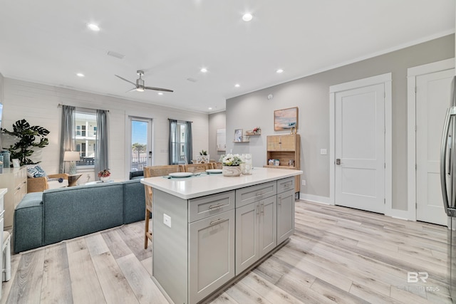 kitchen featuring a center island, crown molding, gray cabinets, light wood-style flooring, and open floor plan