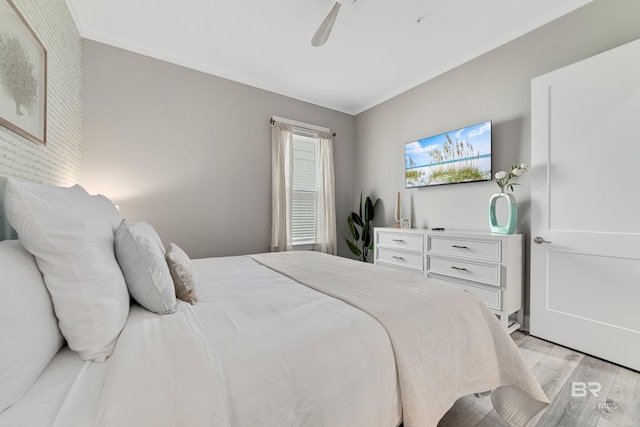 bedroom featuring light wood finished floors, crown molding, and a ceiling fan